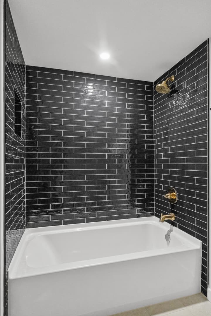Black subway-tile shower with brass fixtures