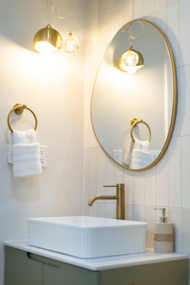 Brass bathroom fixtures and round mirror