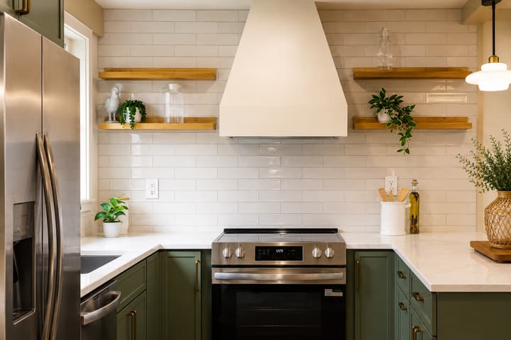 Green shaker kitchen with brass hardware and stainless appliances