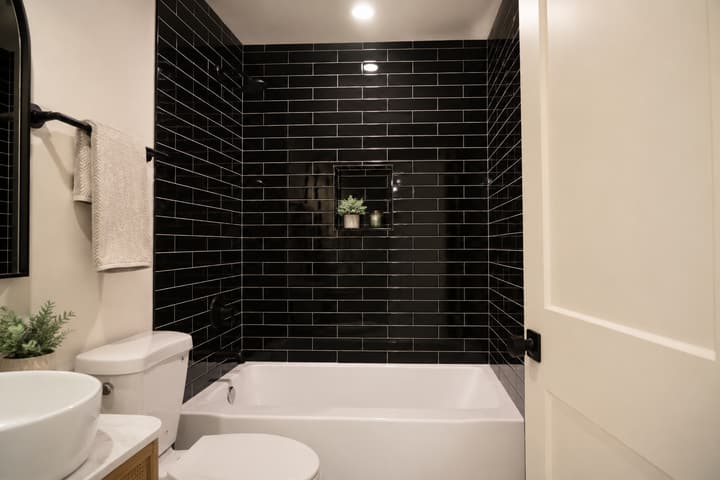 Black tile shower with white tub